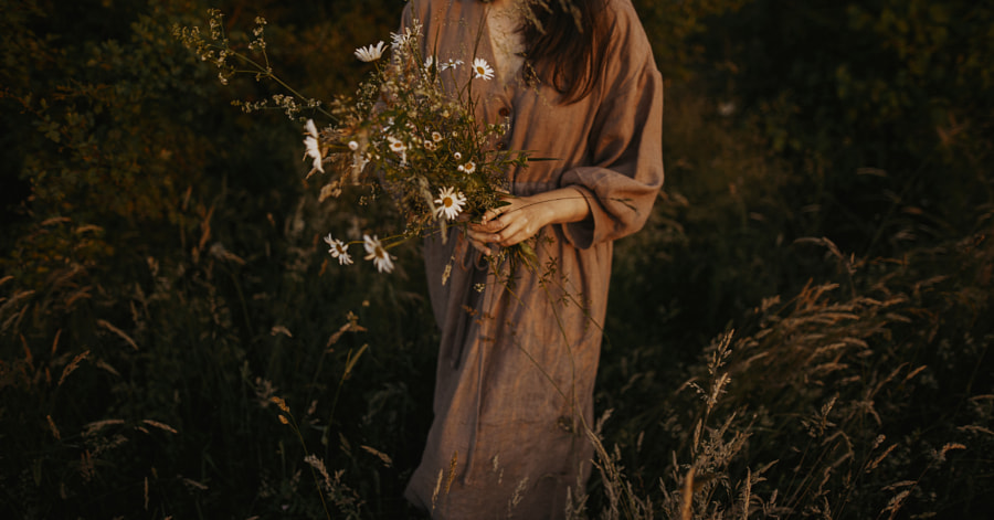 Belle femme en robe de lin rassemblant des fleurs sauvages dans une prairie d'été par Bogdan Sonjachnyj sur 500px.com